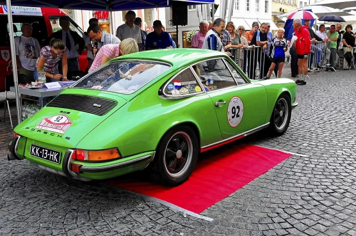 Framed Print : A green Porsche classic car stands on a red carpet surrounded by people