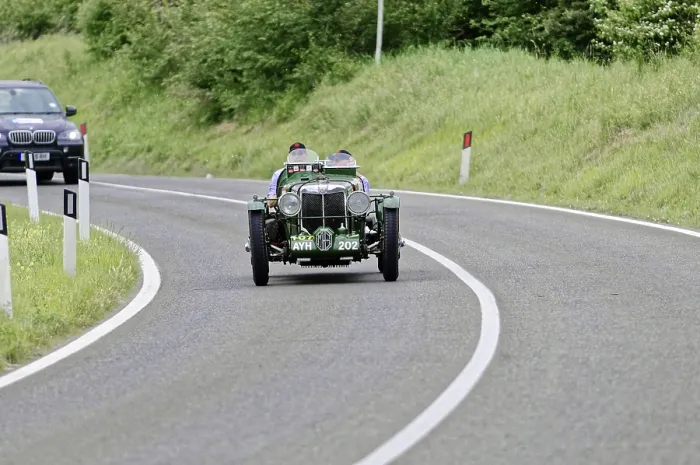Framed Print : Green vintage car drives on winding country road