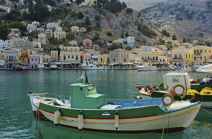 Framed Print : Green and white fishing boat, in the background the houses of Symi Framed Print : Green and white fishing boat, in the background the houses of Symi