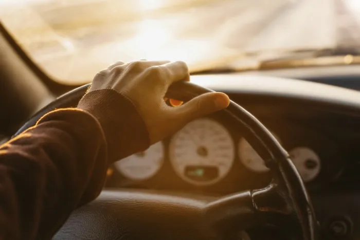 Framed Print : A hand holding a steering wheel inside a car
