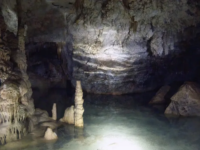 Framed Print : Hand lamp lit underground lake inside stalactite cave with stalactites and stalagmites stalactite formations