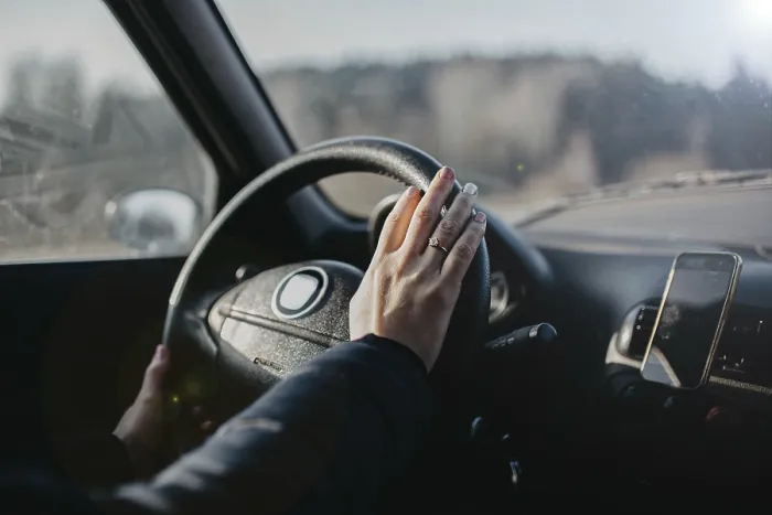 Framed Print : A hand on the steering wheel inside a car with a smartphone holder attached