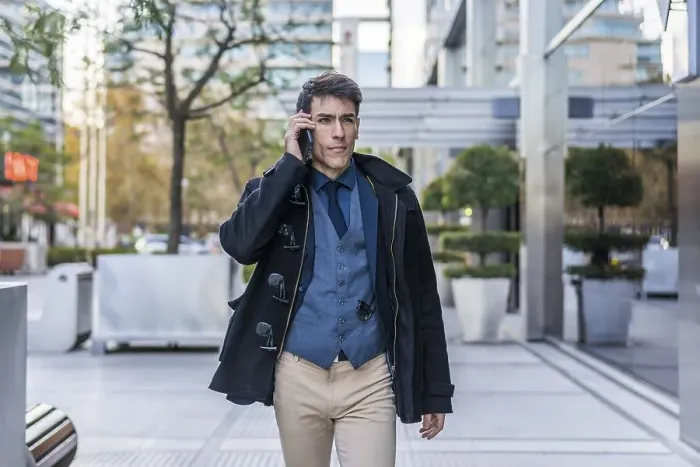 Framed Print : A handsome businessman talking on his cell phone while walking in the street