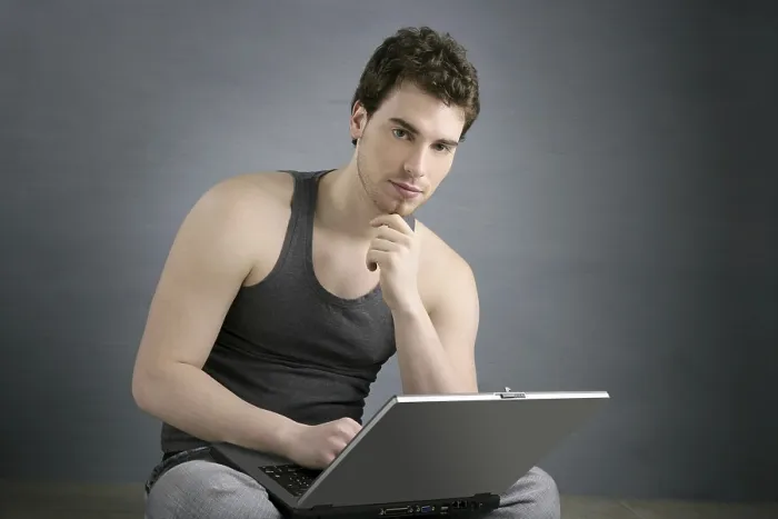 Framed Print : Handsome student young man sit working on laptop over gray background