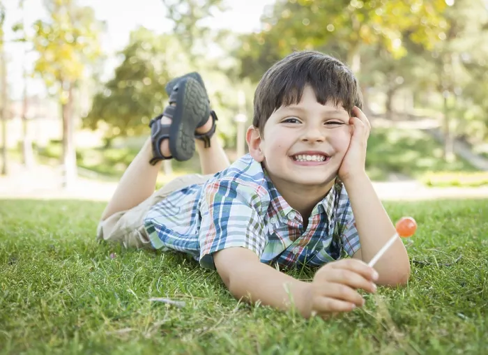Framed Print : Handsome young boy enjoying his lollipop outdoors on the grass