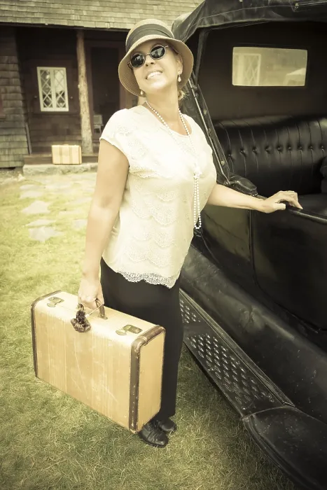 Framed Print : Happy 1920s dressed girl holding suitcase next to vintage car and cabin