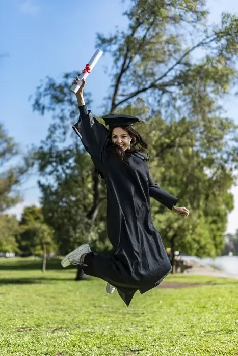 Framed Print : Happy graduated girl in a black gown jumping while holding her diploma