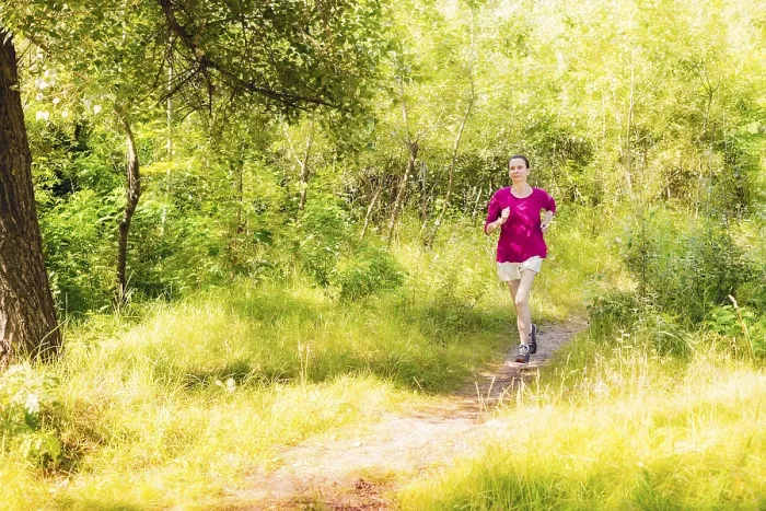 Framed Print : A happy senior woman is running toward the light in the forest during a warm summer day