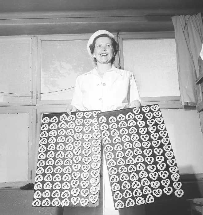 Framed Print : Happy woman in a bakery holding two trays of pretzels ready to bake
