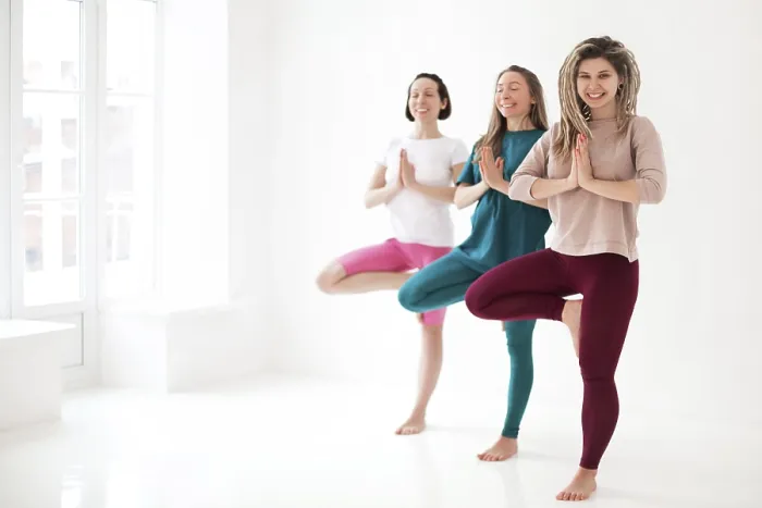Framed Print : Happy young women smiling meditating against white wall during yoga session