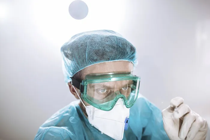 Framed Print : A healthcare worker in protective gear focused on a task
