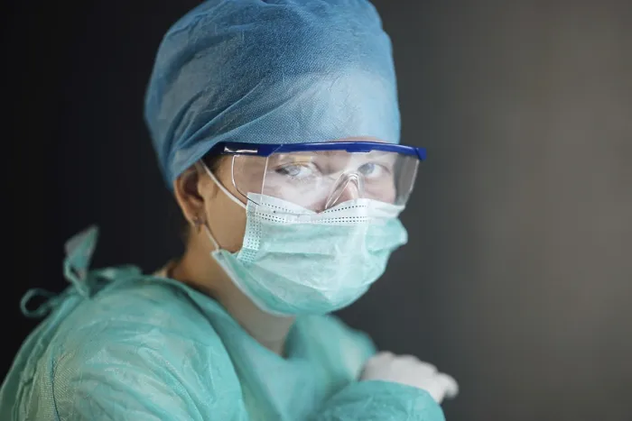 Framed Print : A healthcare worker wearing a mask and goggles looking intently at the camera
