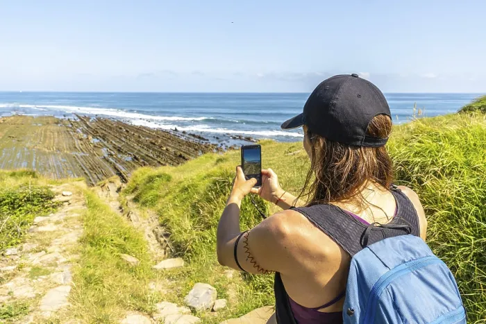 Framed Print : Hiker taking pictures of the impressive flysch cliffs at sakoneta beach in zumaia