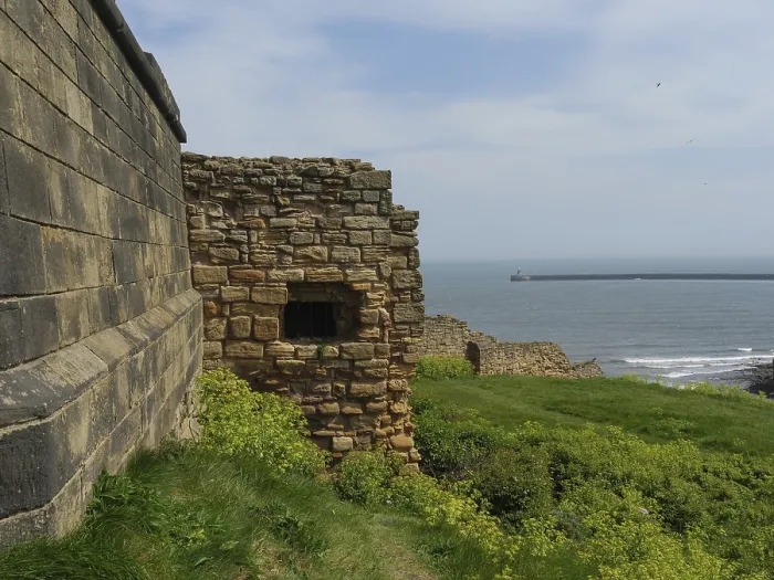 Framed Print : A historic fortress wall in front of the ocean on a sunny day with a green meadow in the foreground