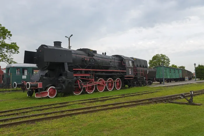 Framed Print : Historic steam locomotive with green wagons on a track under a cloudy sky
