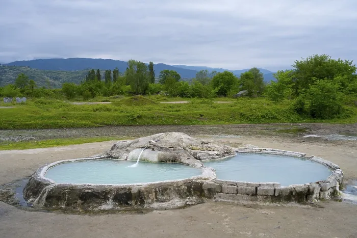 Framed Print : Hot spring pool in open landscape with wooded hills and mountains in the background