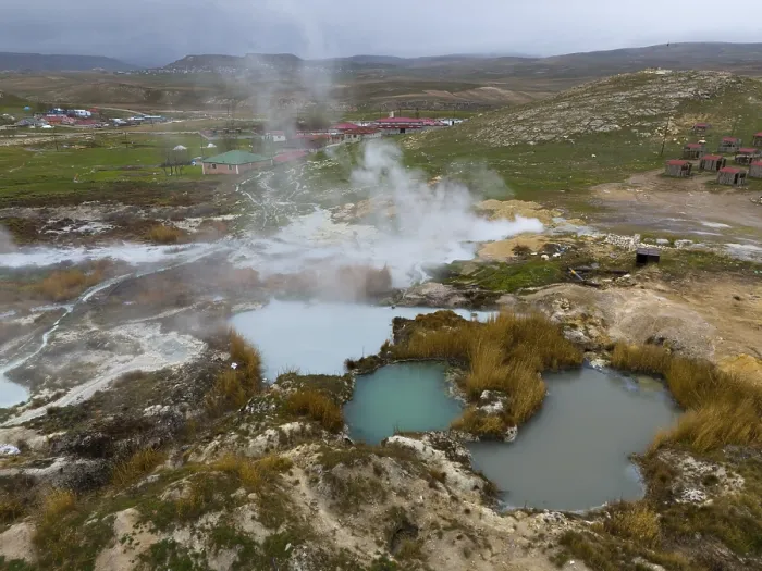 Framed Print : Hot springs with rising steam in a wide landscape with mountains in the background