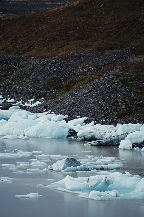 Framed Print : Ice chunks scattered along a rocky shoreline beside still water