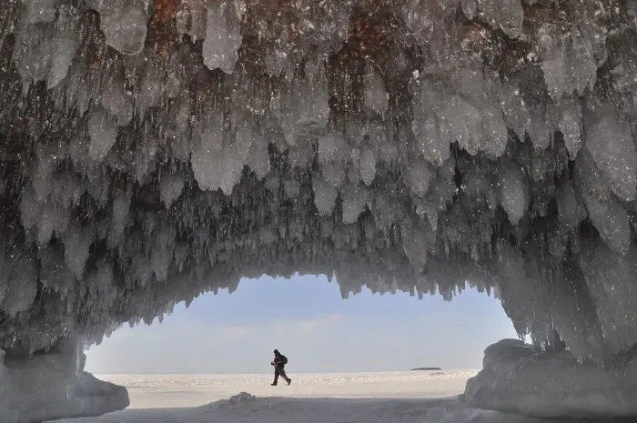 Framed Print : Ice formations and icicles hanging from ceiling in a cave and a man walking on frozen Lake Superior Framed Print : Ice formations and icicles hanging from ceiling in a cave and a man walking on frozen Lake Superior
