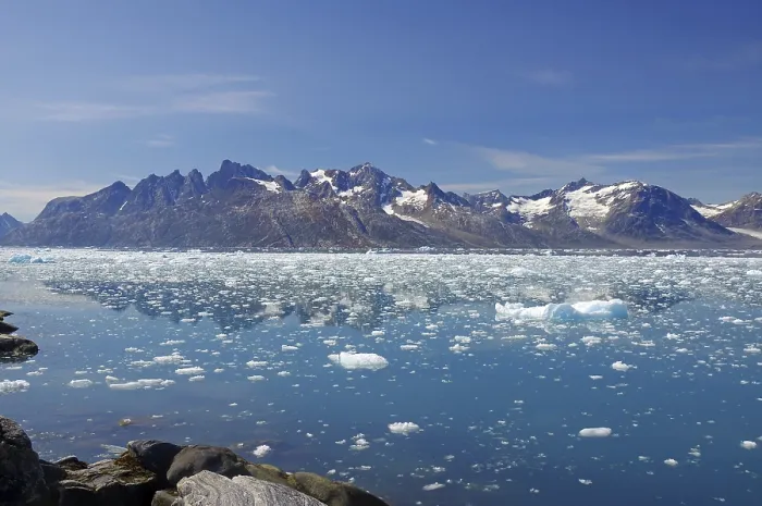 Framed Print : Icebergs floating in crystal clear water with mountains in the background under a blue sky