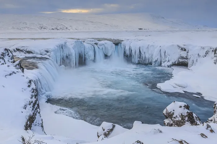 Framed Print : Icy waterfall and rapids in front of a mountain landscape