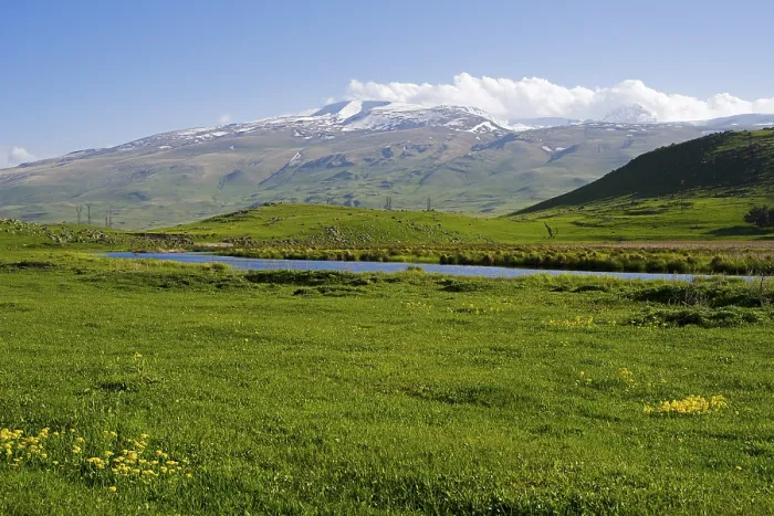 Framed Print : Idyllic landscape with snow-covered mountains and green grass under a blue sky