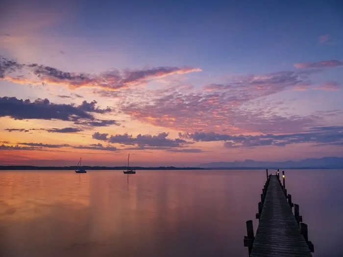 Framed Print : Illuminated clouds over sailing boats and jetty at Chiemsee at dawn