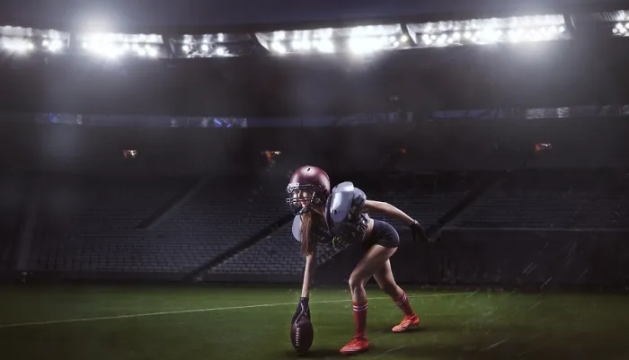 Framed Print : Image of a girl in the uniform of an American football team player preparing to play the ball at the stadium