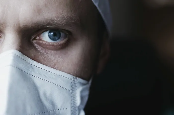 Framed Print : Intense close-up of a masked doctor focusing with piercing blue eyes