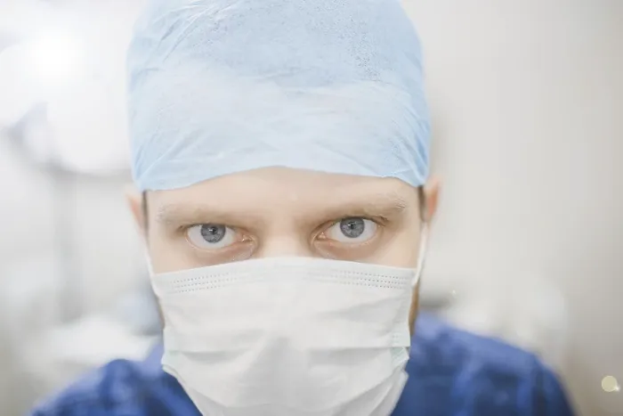 Framed Print : Intense gaze of a doctor wearing a mask and blue surgical cap