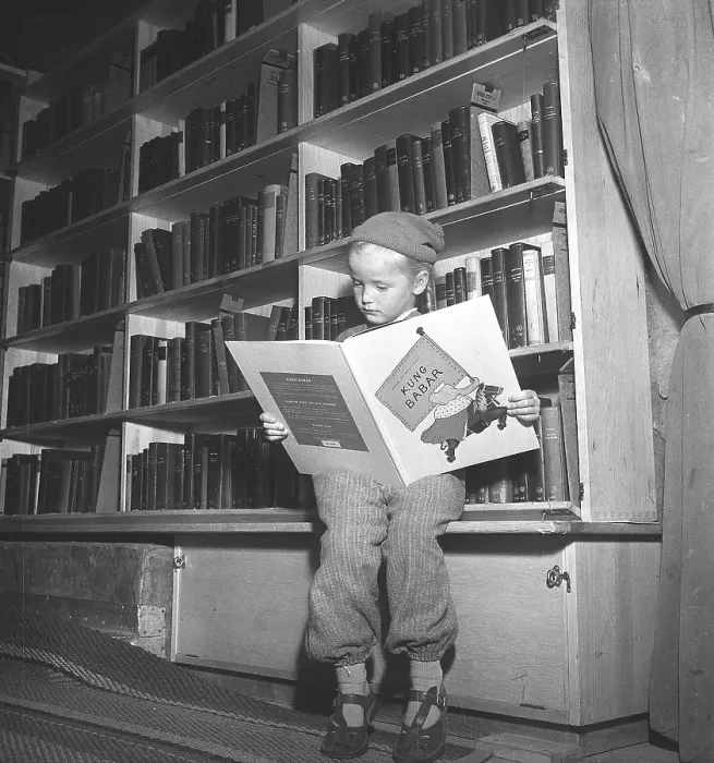 Framed Print : Interior of a bus that served as a mobile library in the 1950s. A boy is reading the book King Babar in one of Malmoe City Library's bookmobiles