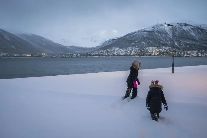 Framed Print : Kids walking in a deep snow in front of waters of a fiord