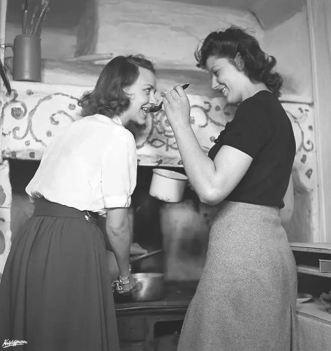 Framed Print : In the kitchen 1940s. Interior of a rural kitchen and two women cooking together