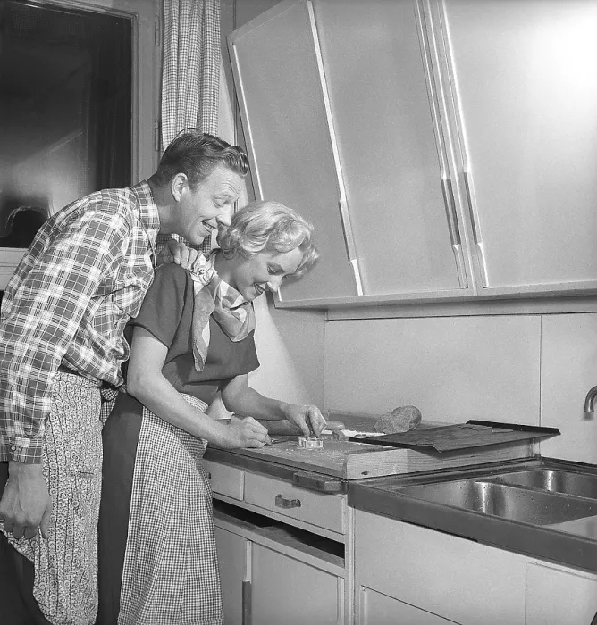 Framed Print : In the kitchen in the 1950s. Ayoung couple baking heart shaped gingerbread cookies for christmas