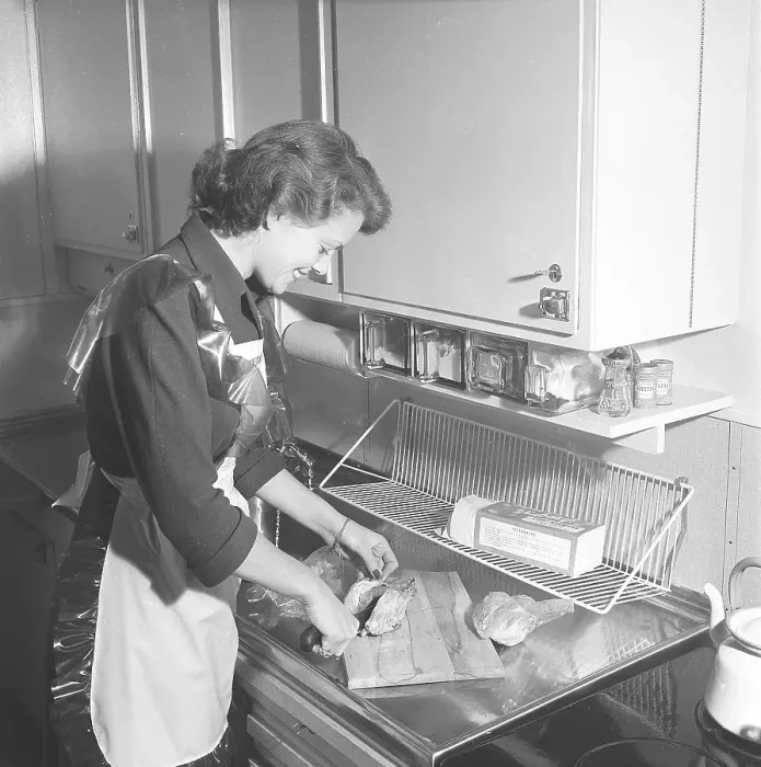 Framed Print : In the kitchen 1950s. Interior of a kitchen and a young woman standing at the kitchen sink preparing the ingredients Framed Print : In the kitchen 1950s. Interior of a kitchen and a young woman standing at the kitchen sink preparing the ingredients