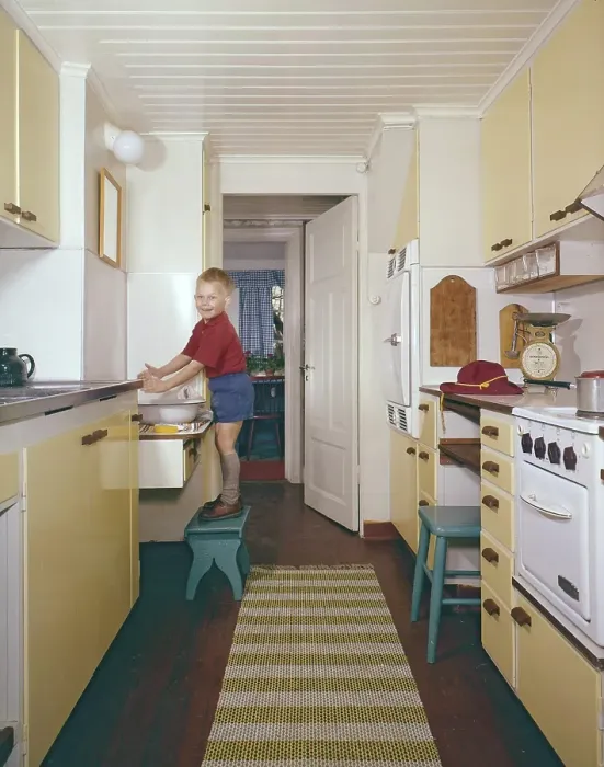 Framed Print : Kitchen of the 50s-60s. A boy is standing on a footstool and washes his hands