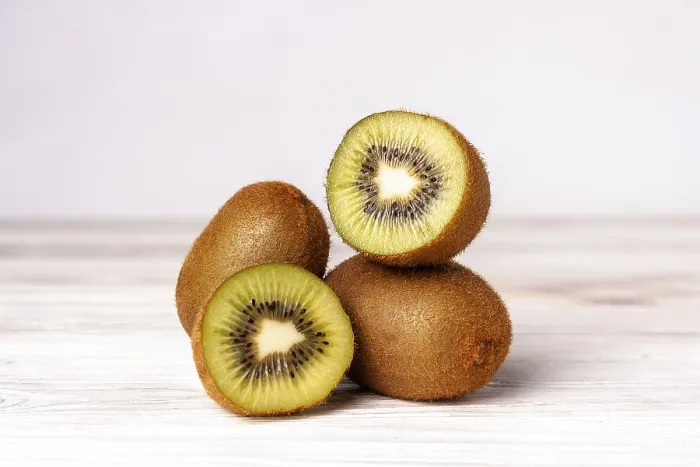 Framed Print : Kiwi slices on a white wooden table