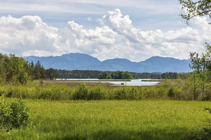 Framed Print : A lake with grassy meadows and mountains in the background under a cloudy sky