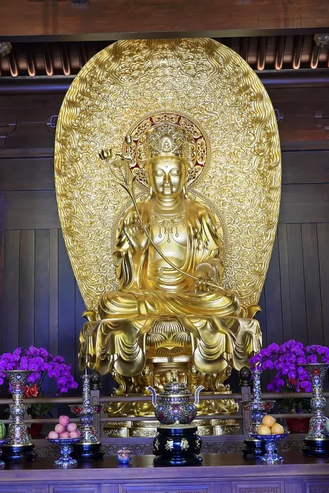 Framed Print : A large golden Buddha statue flanked by flowers in a temple