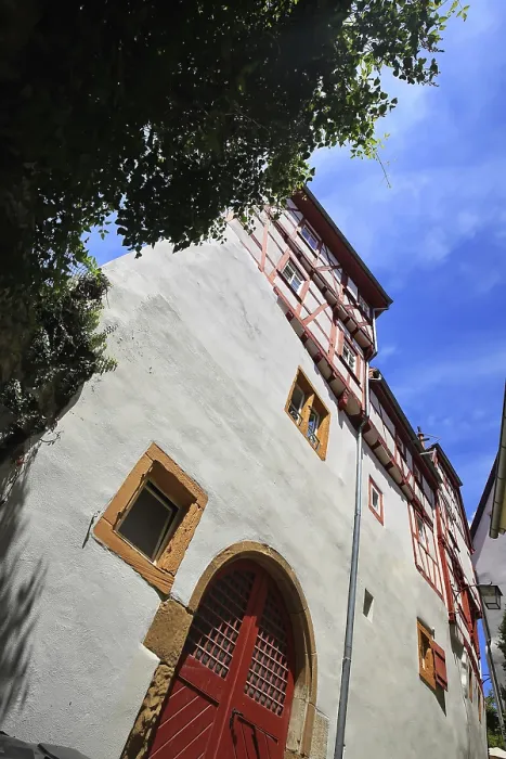 Framed Print : Large half-timbered house with red doors and windows under a blue sky in Bad Wimpfen