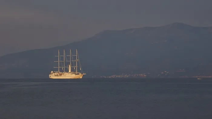 Framed Print : A large sailing ship sails in calm seas against a mountain backdrop at dusk