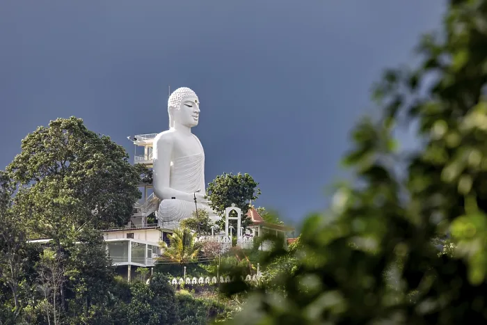 Framed Print : Large white Buddha statue on a hill surrounded by lush nature under blue sky