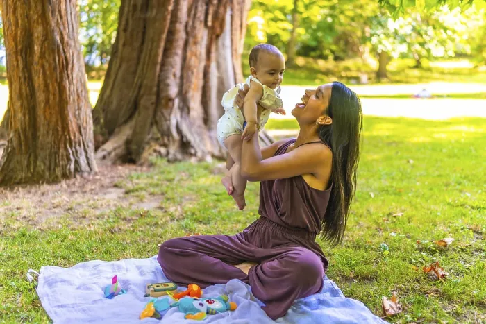 Framed Print : Latin mother joyfully lifting her baby daughter while sitting on a blanket in a park