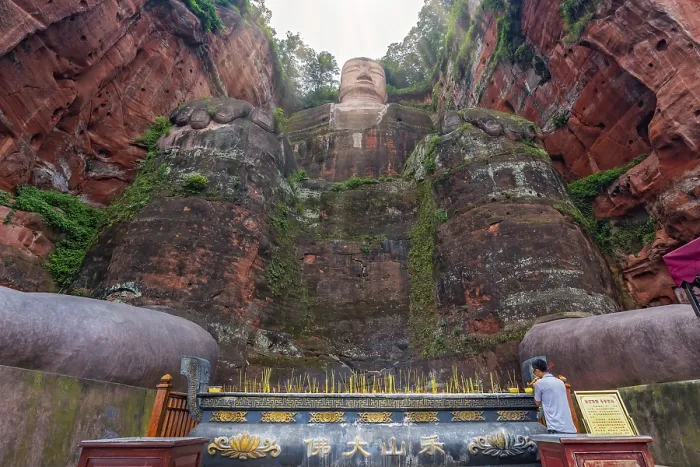 Framed Print : Leshan, China - July 2019 : Chinese male pilgrim lightening memorial candles at the bottom of The Giant Leshan Buddha
