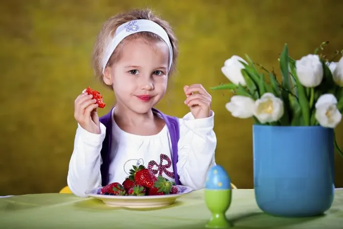 Framed Print : Little blonde girl eating strawberries at a table