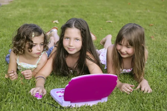 Framed Print : Three little girl outdoor playing with toy computer in grass Framed Print : Three little girl outdoor playing with toy computer in grass