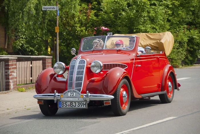 Framed Print : Lively red vintage convertible with top down and passengers on board