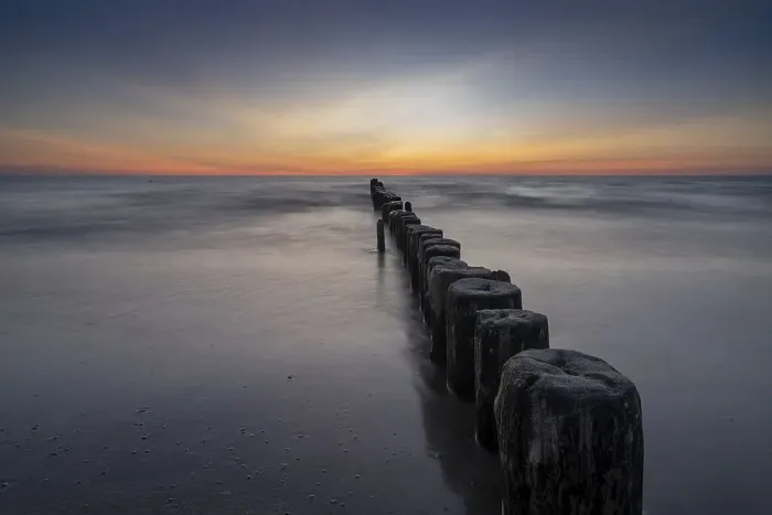 Framed Print : long exposure view of an ocean sunset with sandy beach and wooden pylon storm groin in the foreground