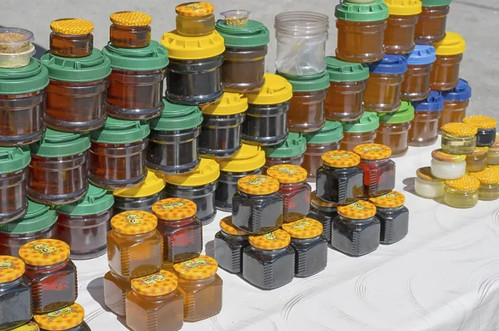 Framed Print : Lots of colorful honey jars with various lids on a market stand
