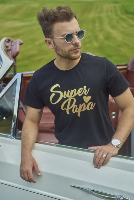 Framed Print : Man in a black shirt and sunglasses leaning against a white convertible in a green field